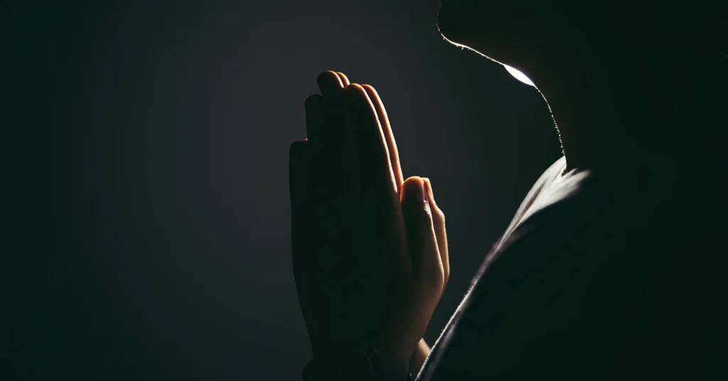 An image showing a person praying with a serene background.