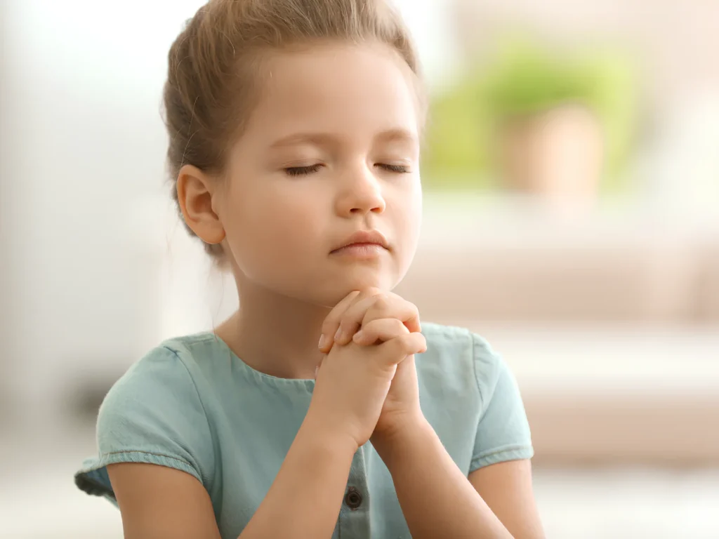 An image showing a person praying with hands clasped and eyes closed.